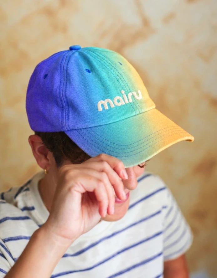 Gorra con degradado azul y naranja con el logotipo de Mairu Studio
