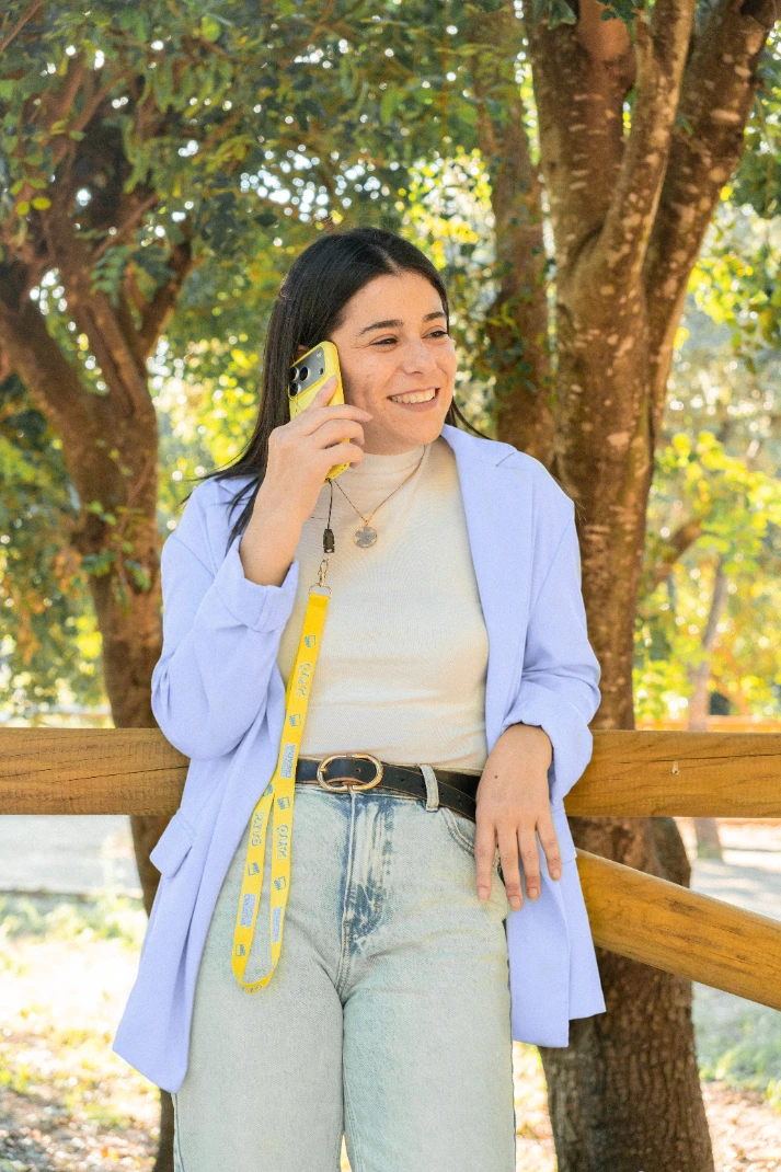 Marina apoyada en una valla de madera, hablando por el móvil con el lanyard de PA'TÓ